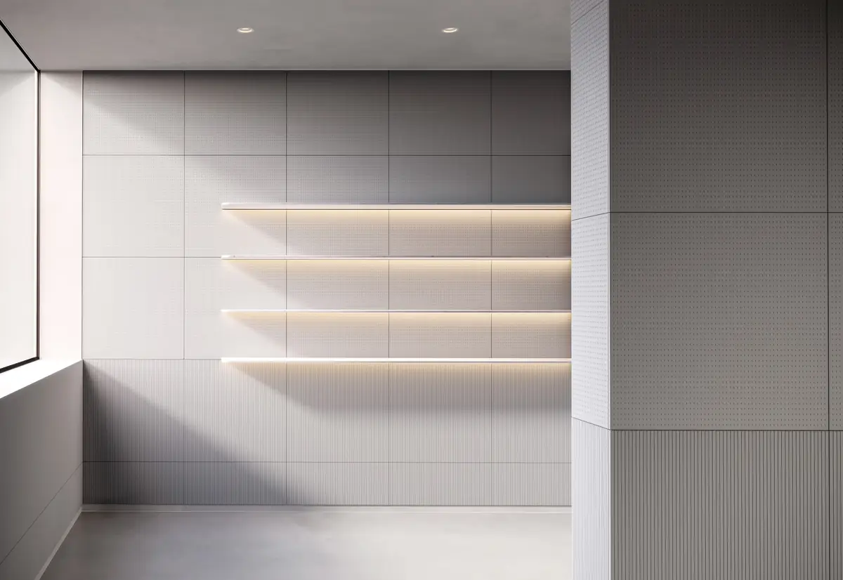 Espacio comercial con estantes iluminados y paredes revestidas de paneles grises con distintos relieves