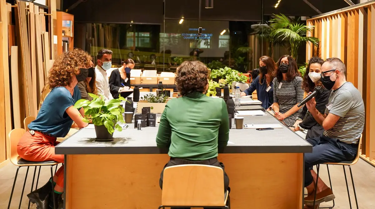 Participants wearing face masks seated around a large table with plants at Matter Barcelona