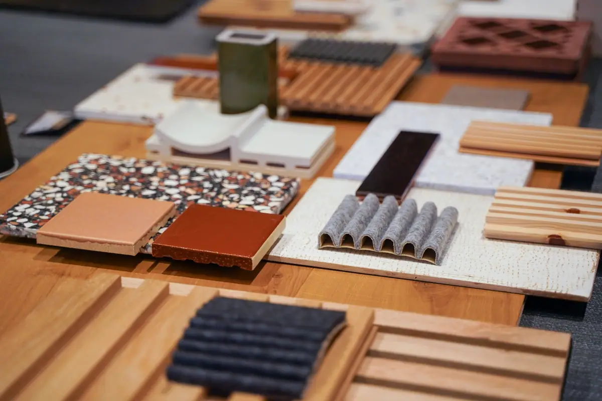 Samples of terrazzo, glazed ceramics, timber slats and felt on a wooden table