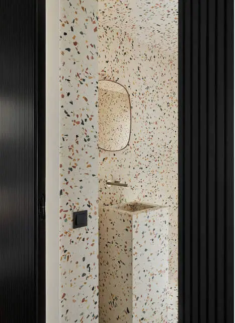 Washroom clad in white terrazzo with coloured aggregate and a freestanding washbasin in the same material