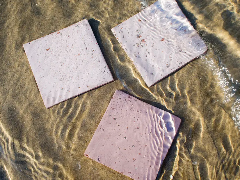 Tres baldosas cuadradas rosadas con punteado sobre la arena bajo el agua