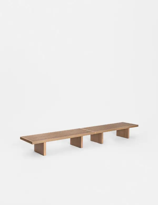 Low bench of pale wooden slats resting on three solid supports.