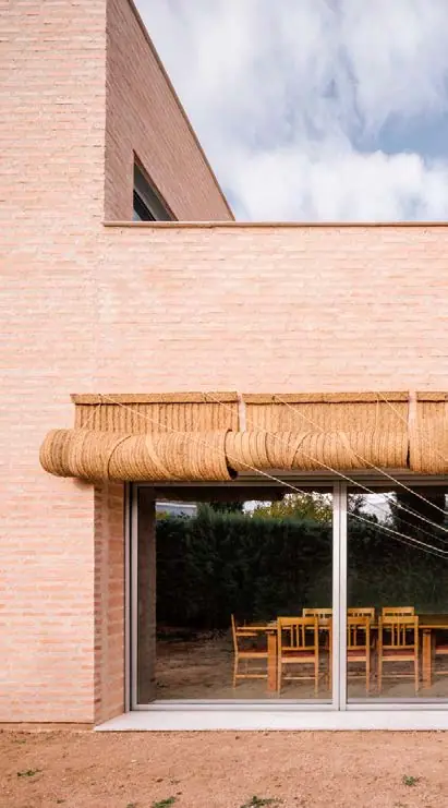 Brick façade of Casa MS5 with a large glazed opening and a woven-fibre awning