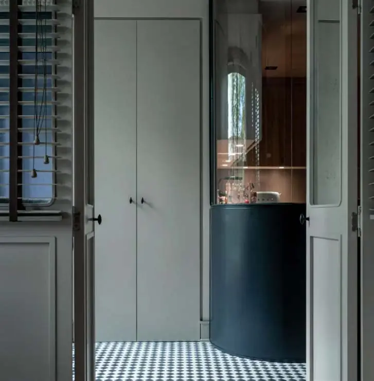 Wooden doors with open shutters leading to a bathroom with a black and white chequerboard floor
