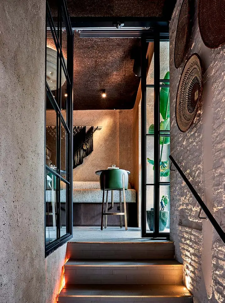 Staircase with a brick wall, niches with clay pots and handmade plates lit with warm light