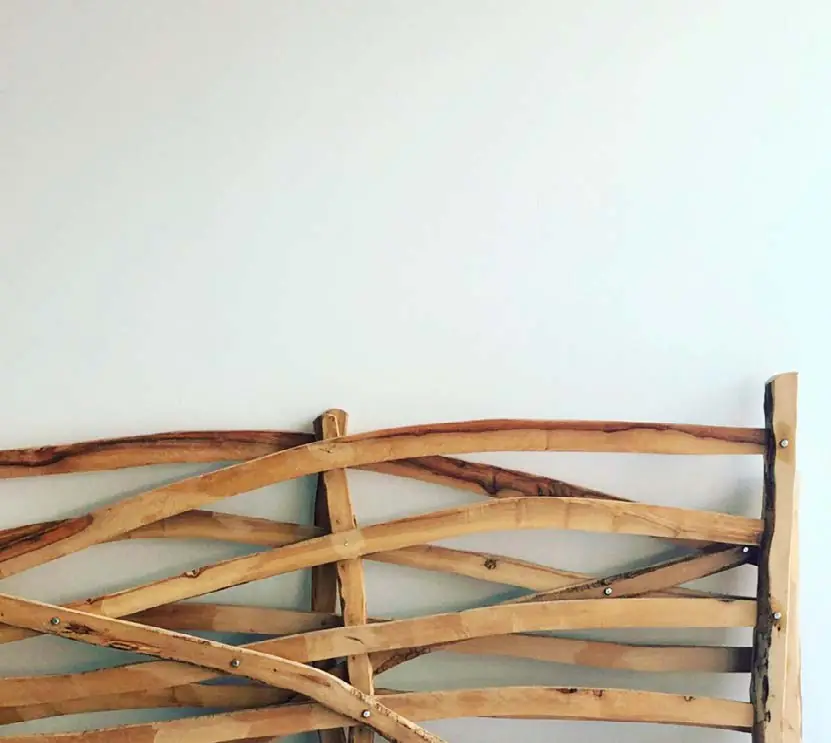 Wooden piece made of assembled olive branches against a white wall