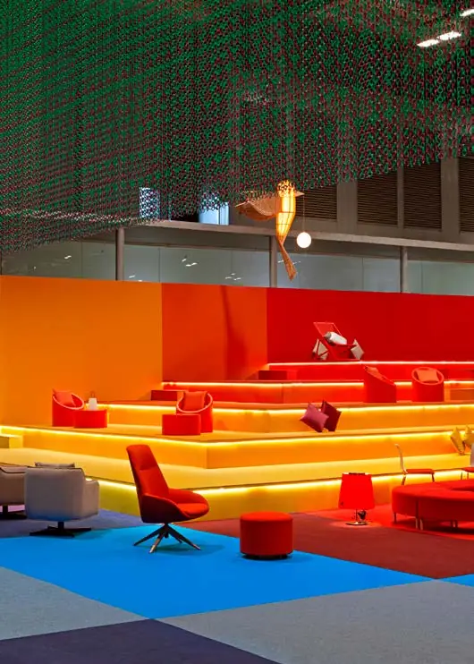 Orange and red tiered seating beneath a curtain of coloured metal chains in the ARCO VIP Lounge