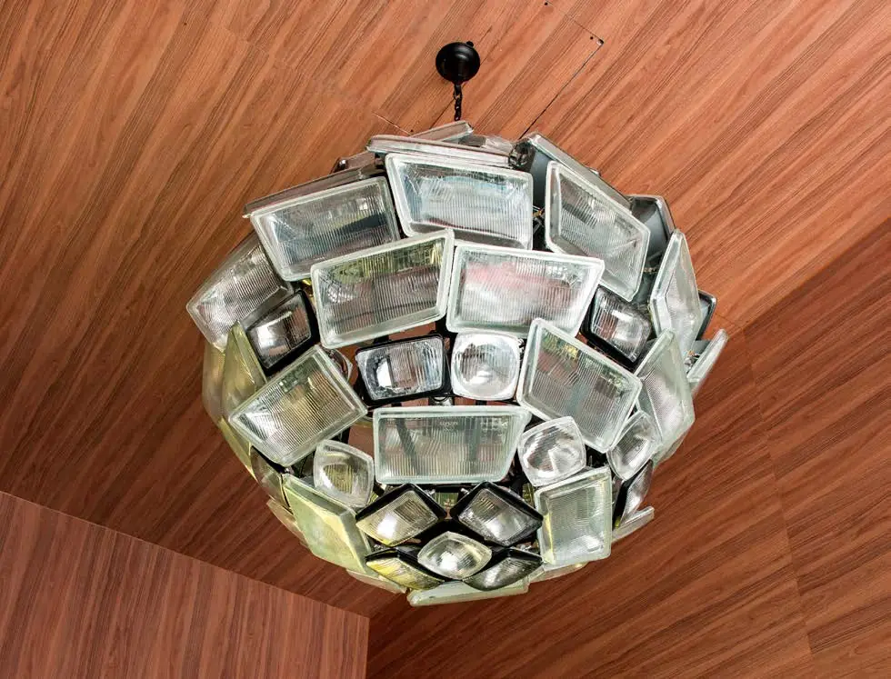 Spherical lamp made of reused car headlights hanging from a wooden ceiling