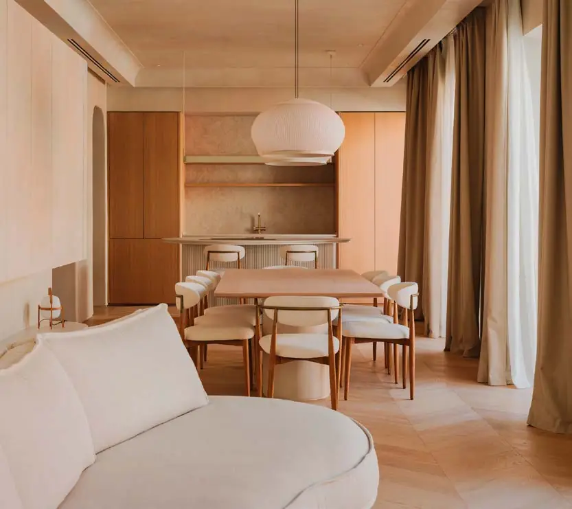 Living and dining room with pale microcement walls, oak floor and a curved sofa