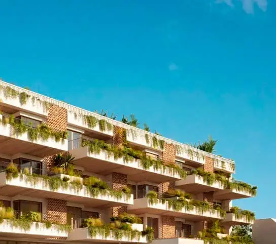 Residential façade with stepped terraces covered in planting under a blue sky