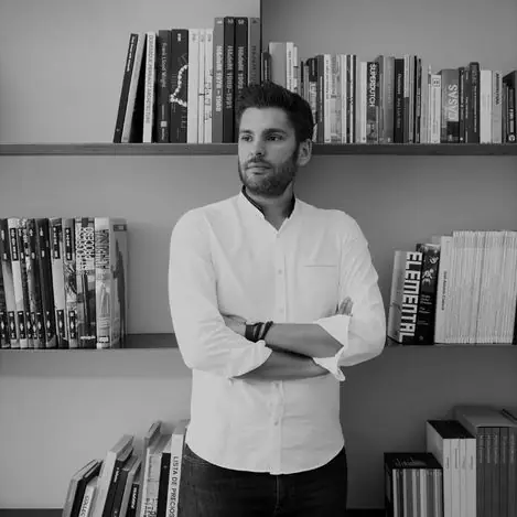 Retrato en blanco y negro de Jaime Prous ante una librería