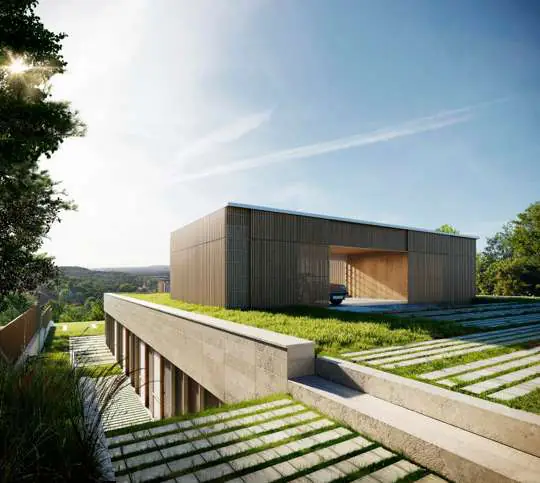 Imagen de la vivienda de Corbera, un volumen bajo con cubierta verde integrado en la pendiente