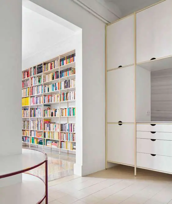 Casa Cruce: mobiliario blanco a medida y una librería que enmarca el paso entre estancias