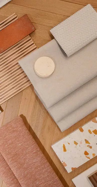 Muestras de tejidos en tonos claros y rosados junto a piezas de madera y terrazo
