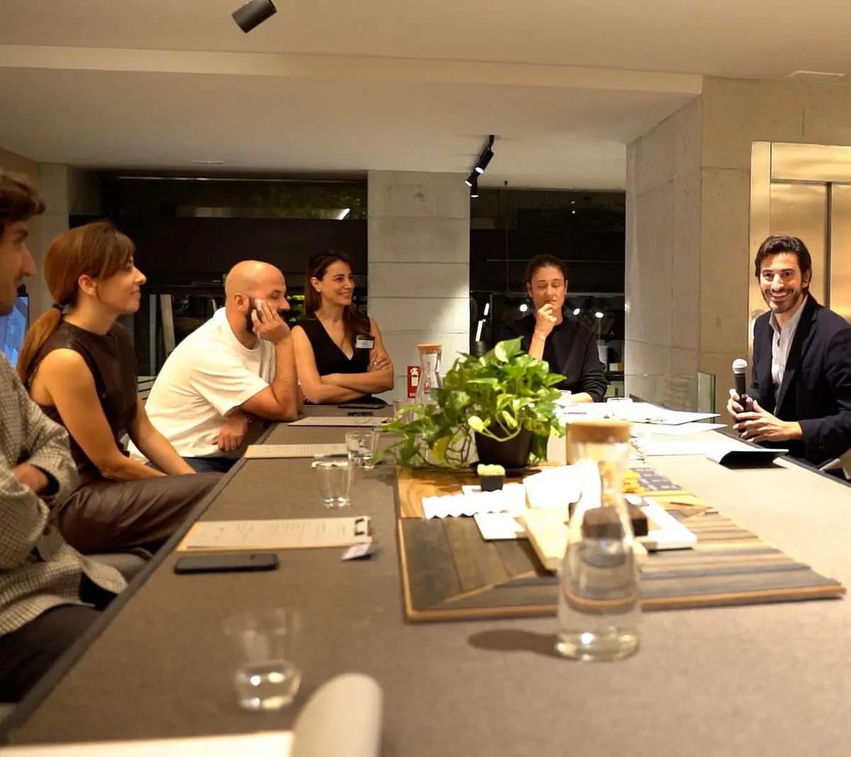 Participants seated on both sides of the materials table listening to a contribution