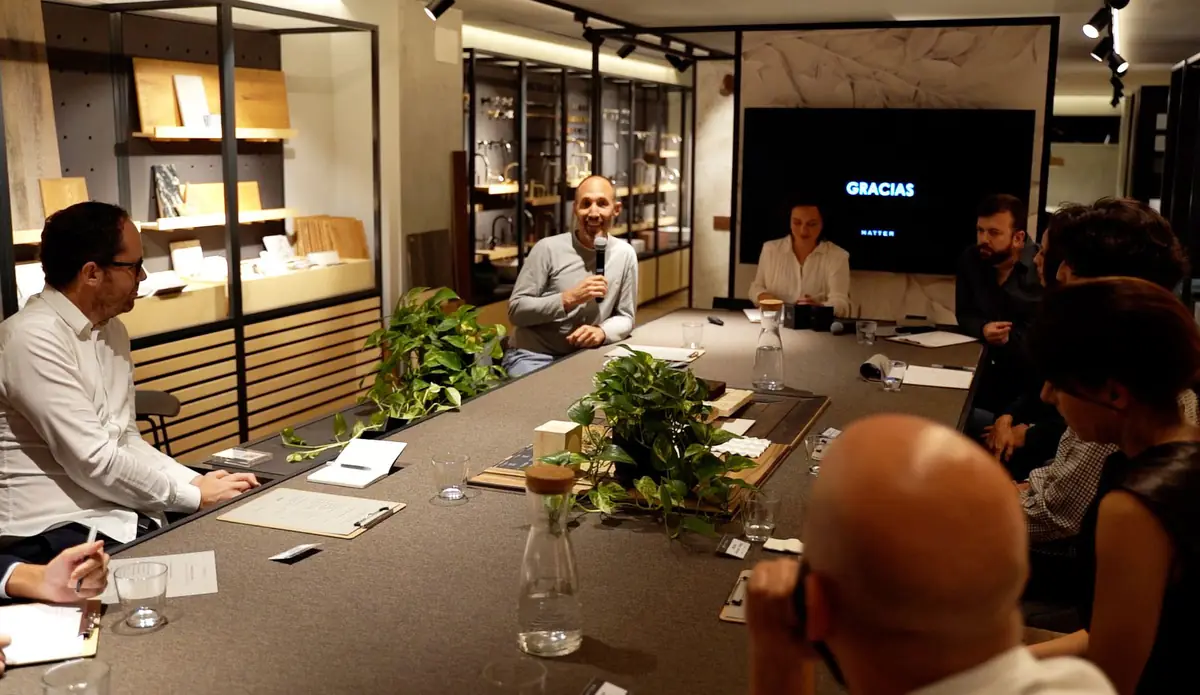 A speaker talking into a microphone in front of the other participants seated at the table