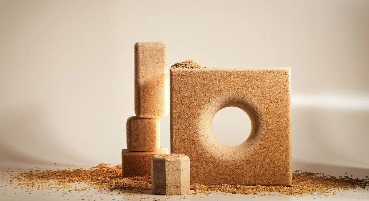 Rice husk board blocks and a panel with a circular hole, surrounded by loose husk