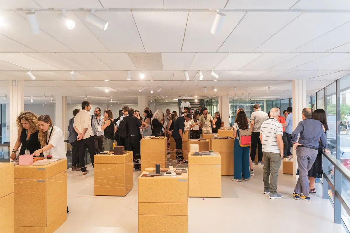 General view of the exhibition with rice husk board totems and visitors in the Altillo of the COAC