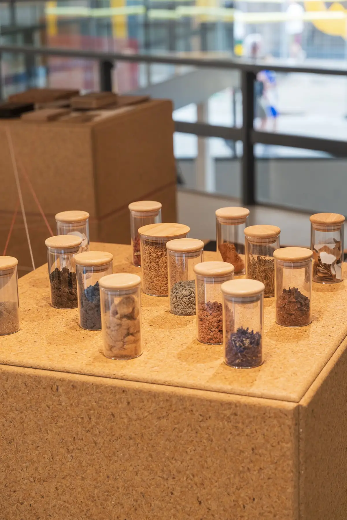 Glass jars containing waste and raw materials on a rice husk board totem
