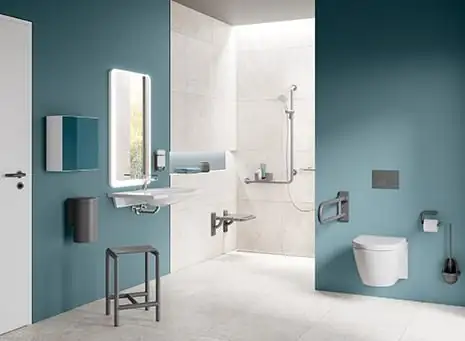 Baño accesible con paredes azul petróleo, lavabo, asiento de ducha y barra abatible junto al inodoro