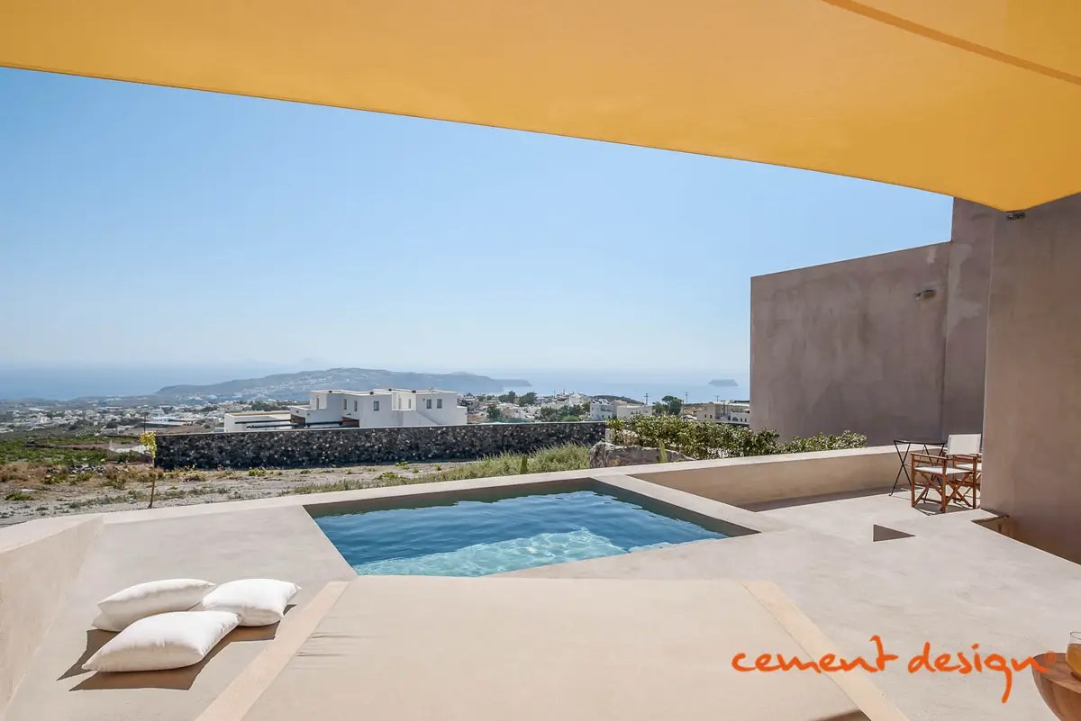Terraza con piscina y tumbonas, con pavimento y muros continuos de cemento decorativo en tonos arena