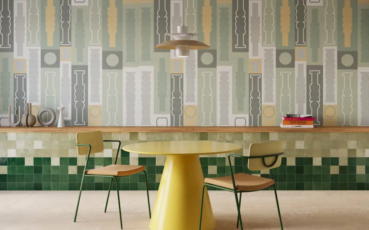 Comedor con mesa amarilla y dos sillas ante una pared cerámica con dibujo de balaustres y un zócalo de azulejos verdes.