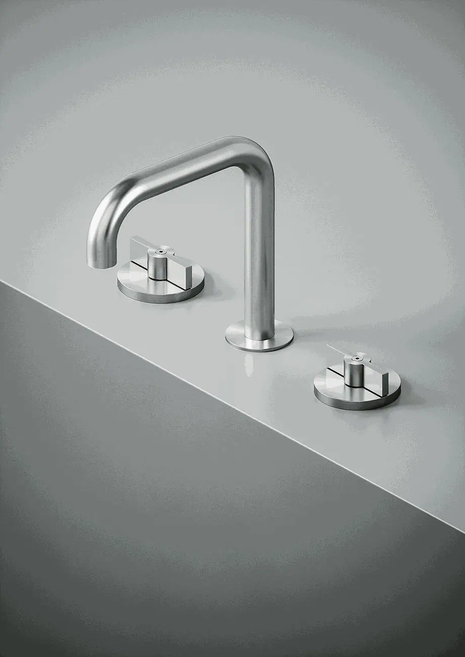 Deck-mounted steel basin tap with a curved spout and two round handles on a grey worktop