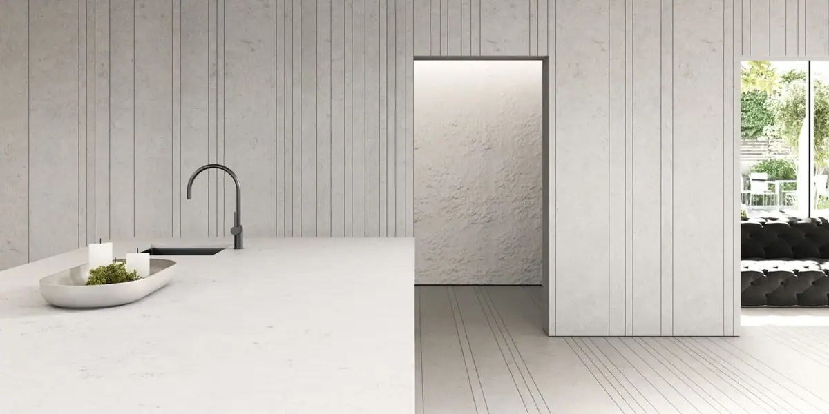Kitchen with an island in Obsidiana Volcano Light and pale walls and floor with vertical joints
