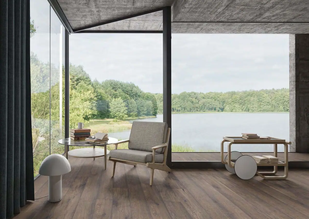 Living room with large windows overlooking a lake, a wooden armchair and dark wood-look plank flooring