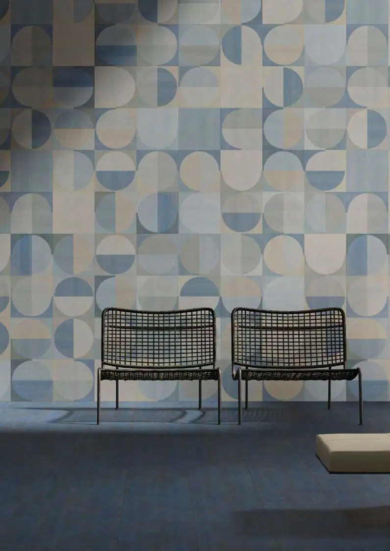Wall with a geometric pattern of circles and semicircles in blues and beige, with two black cane chairs on a blue floor