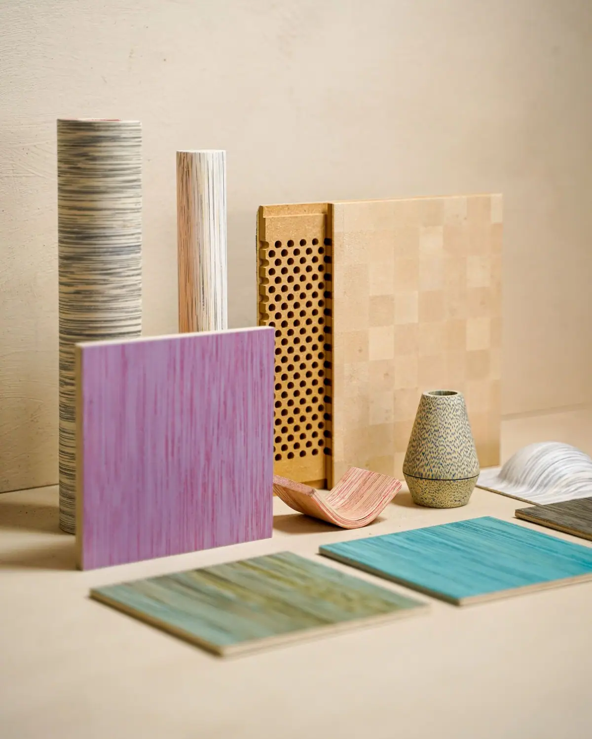 Samples of stained wood, perforated boards and turned pieces on a neutral background