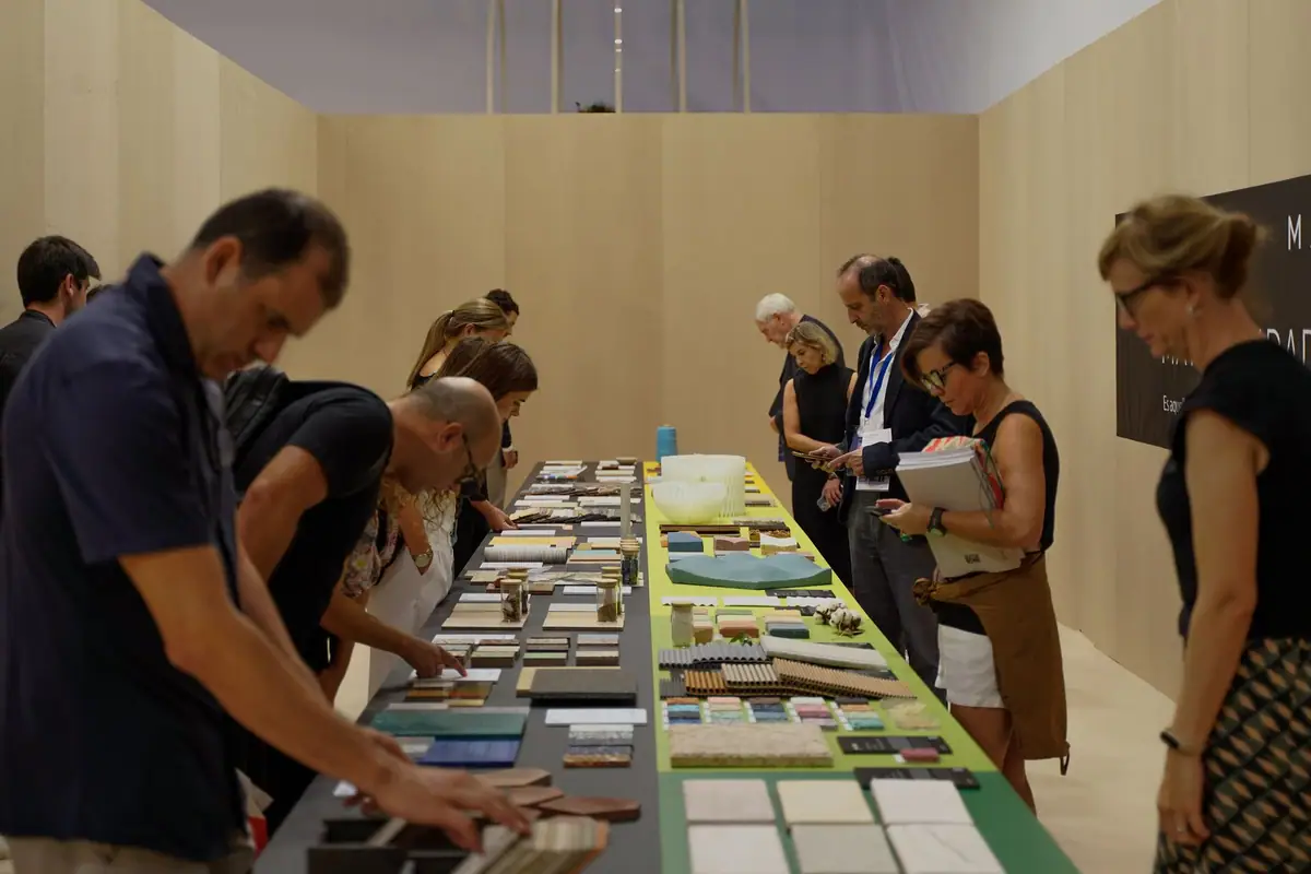 Visitors look at the material samples on the long exhibition table