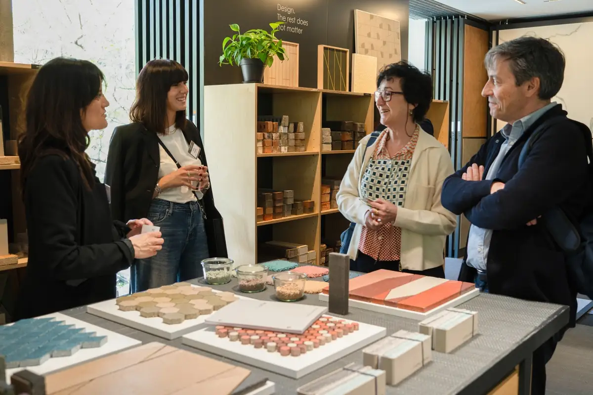 Cuatro personas conversan ante una mesa con muestras de piezas cerámicas