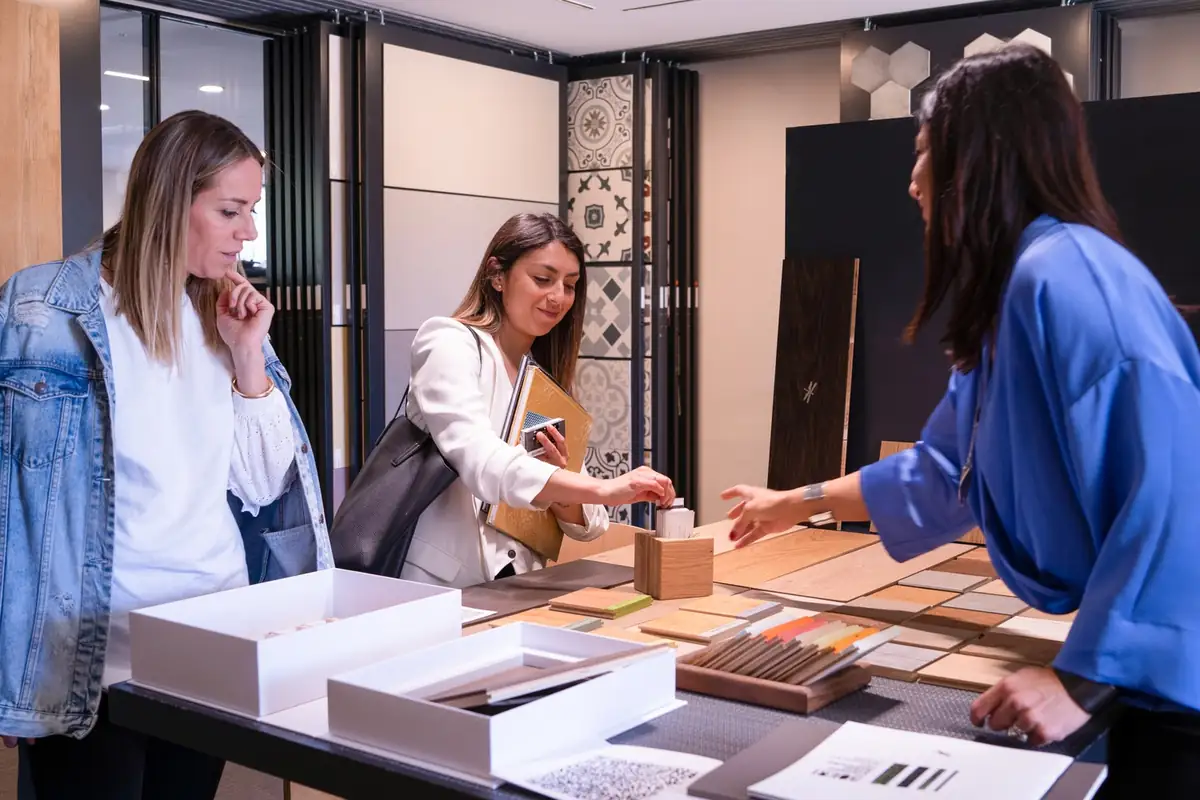 Tres mujeres conversan ante una mesa con muestras de madera