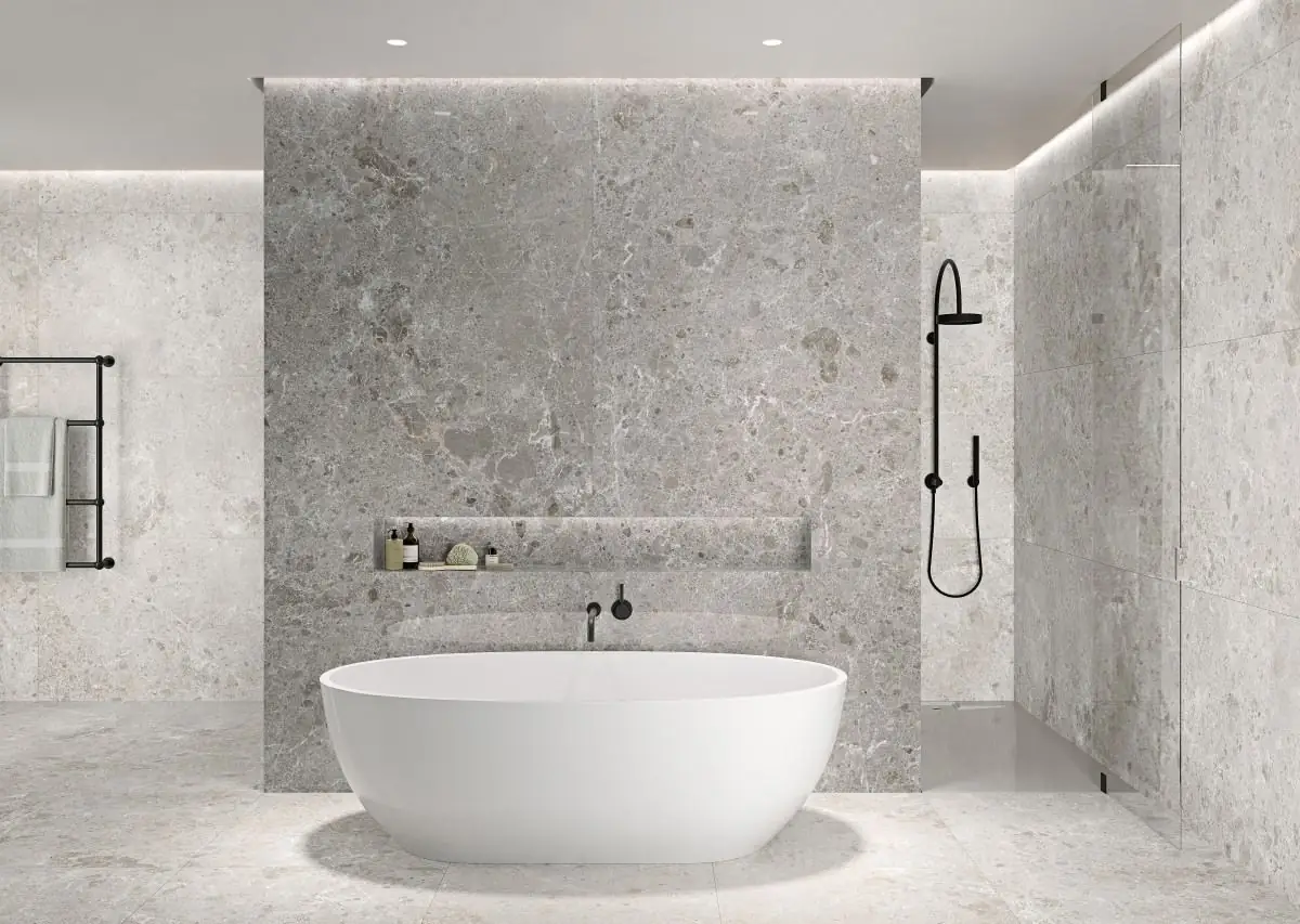 Bathroom with a white freestanding bath and walls and floor clad in grey stone-effect porcelain in large-format slabs
