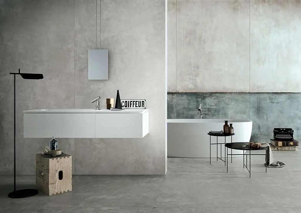 Bathroom with a wall-hung washbasin and a bath against walls of grey and greenish render-effect porcelain