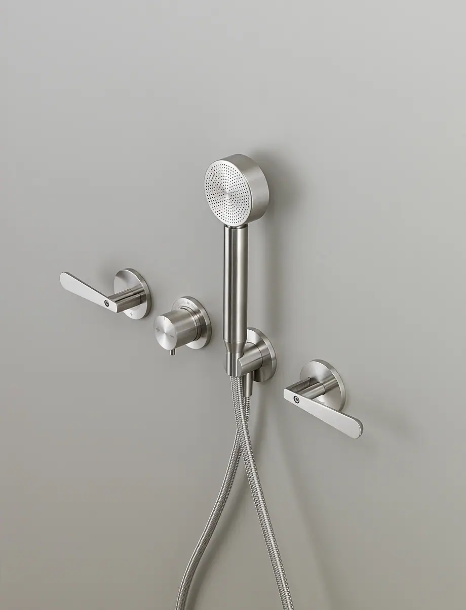 Wall-mounted steel shower set with two handles, a central thermostatic mixer and a round hand shower with a metal hose
