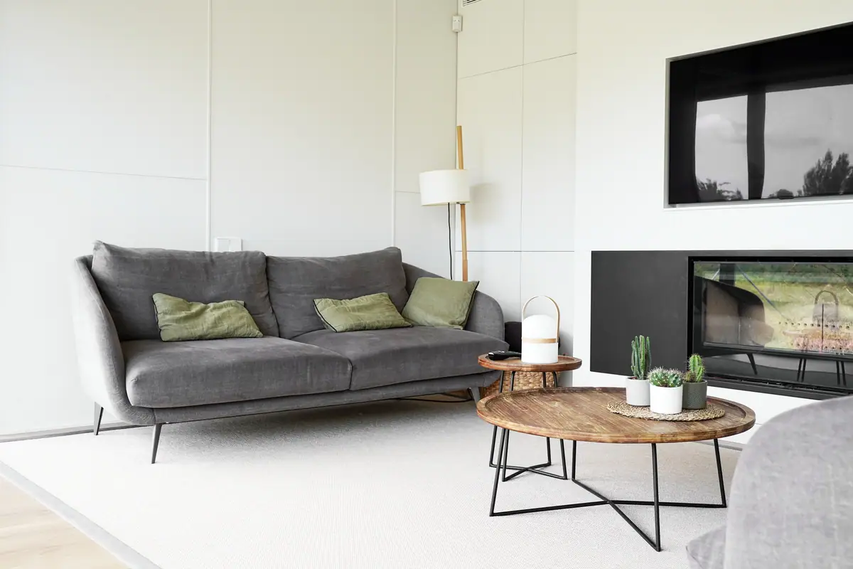 Living room of Casa Om with a grey sofa, wooden side tables and a fireplace set into a white wall