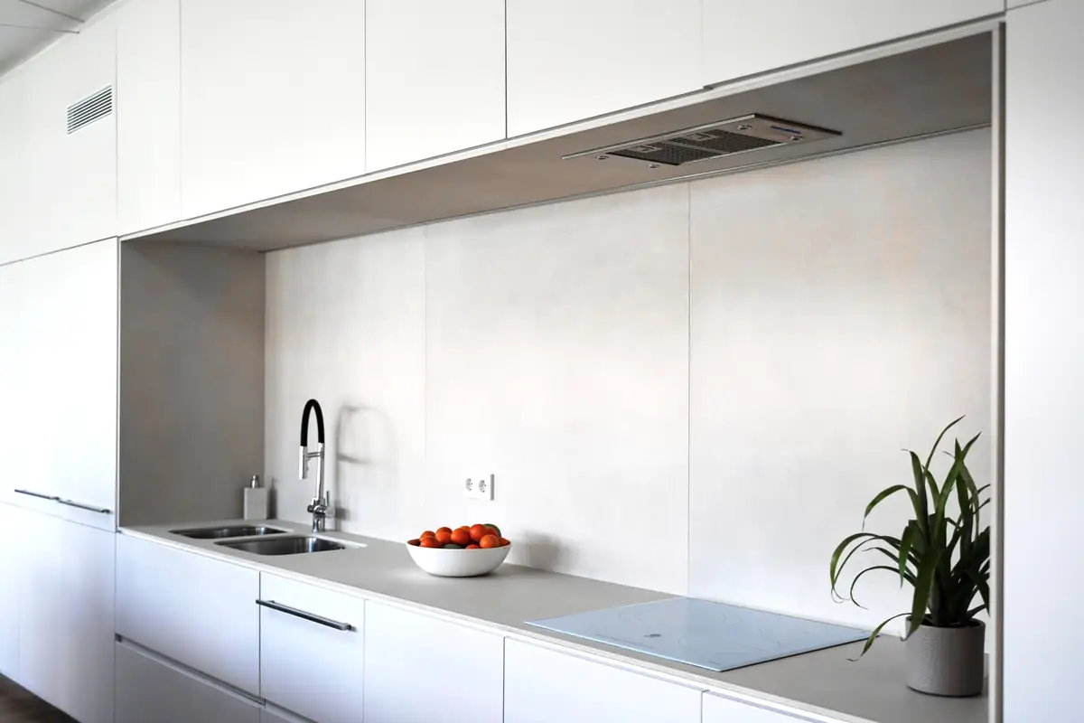 White linear kitchen with a light-toned recess, sink, induction hob and integrated extractor hood