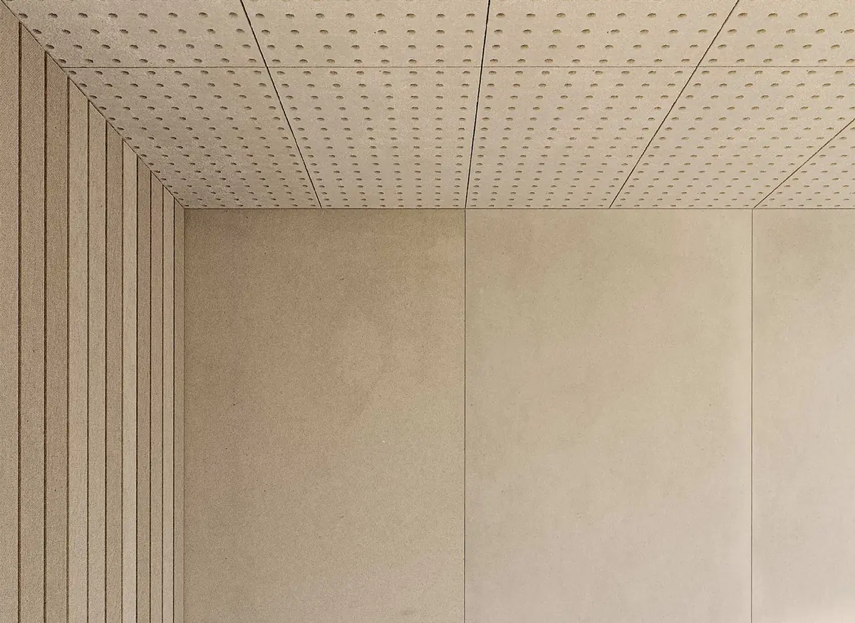 Ceiling of perforated boards and walls of plain and grooved light beige boards.
