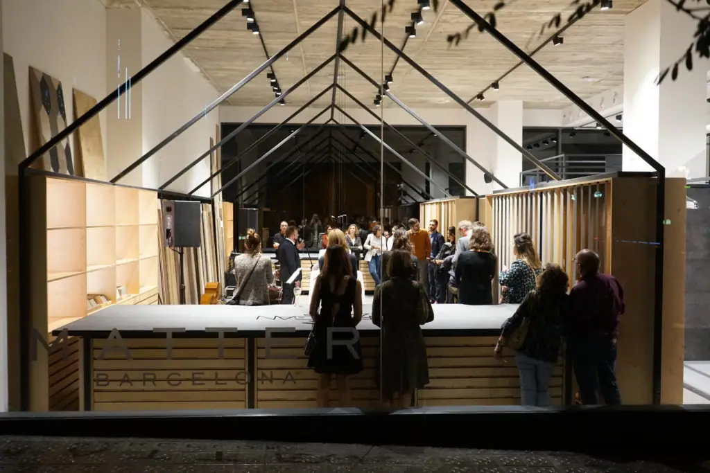 Guests around the wooden reception counter at the entrance, beneath a house-shaped metal structure