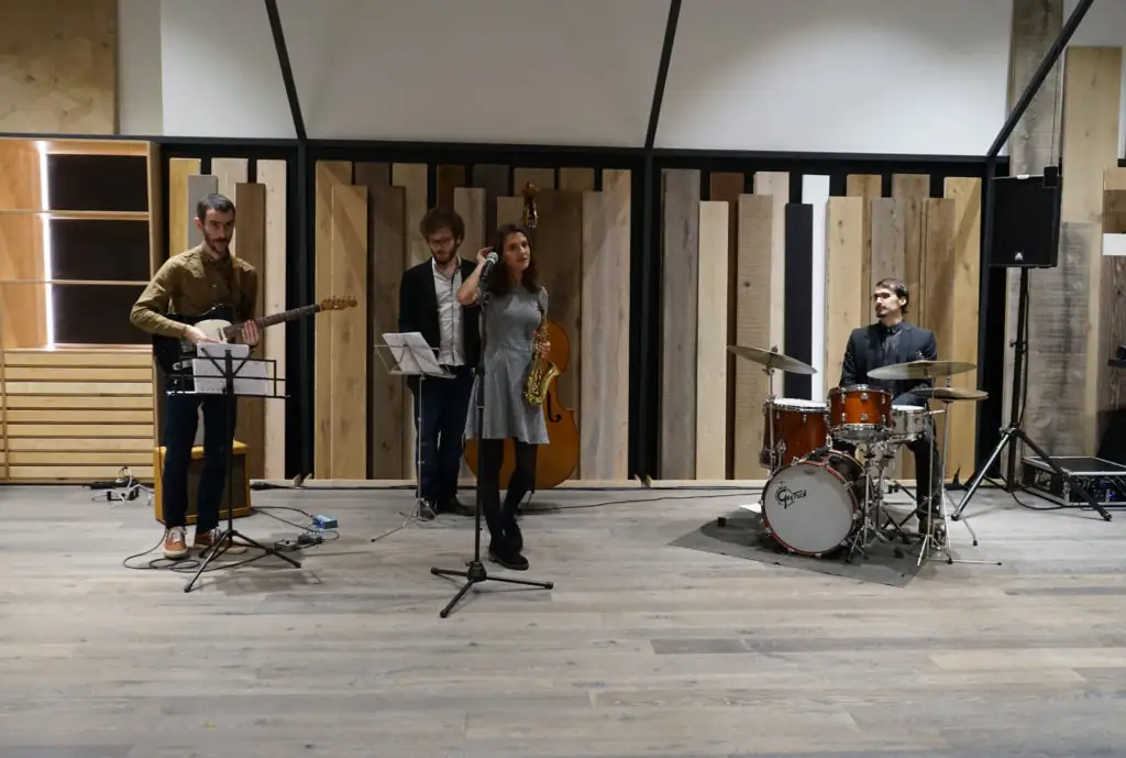 Jazz band with guitar, saxophone and drums playing in front of the wood displays