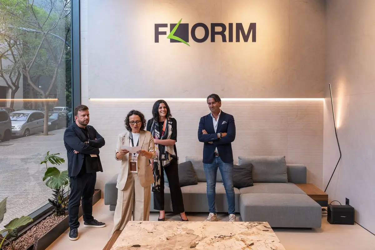 Four people standing beneath the Florim logo presenting the space, next to a sofa and a stone table
