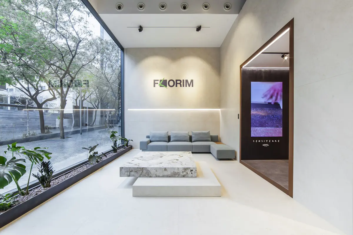 Living area with a grey sofa, a low stone table and the Florim logo facing the shop window
