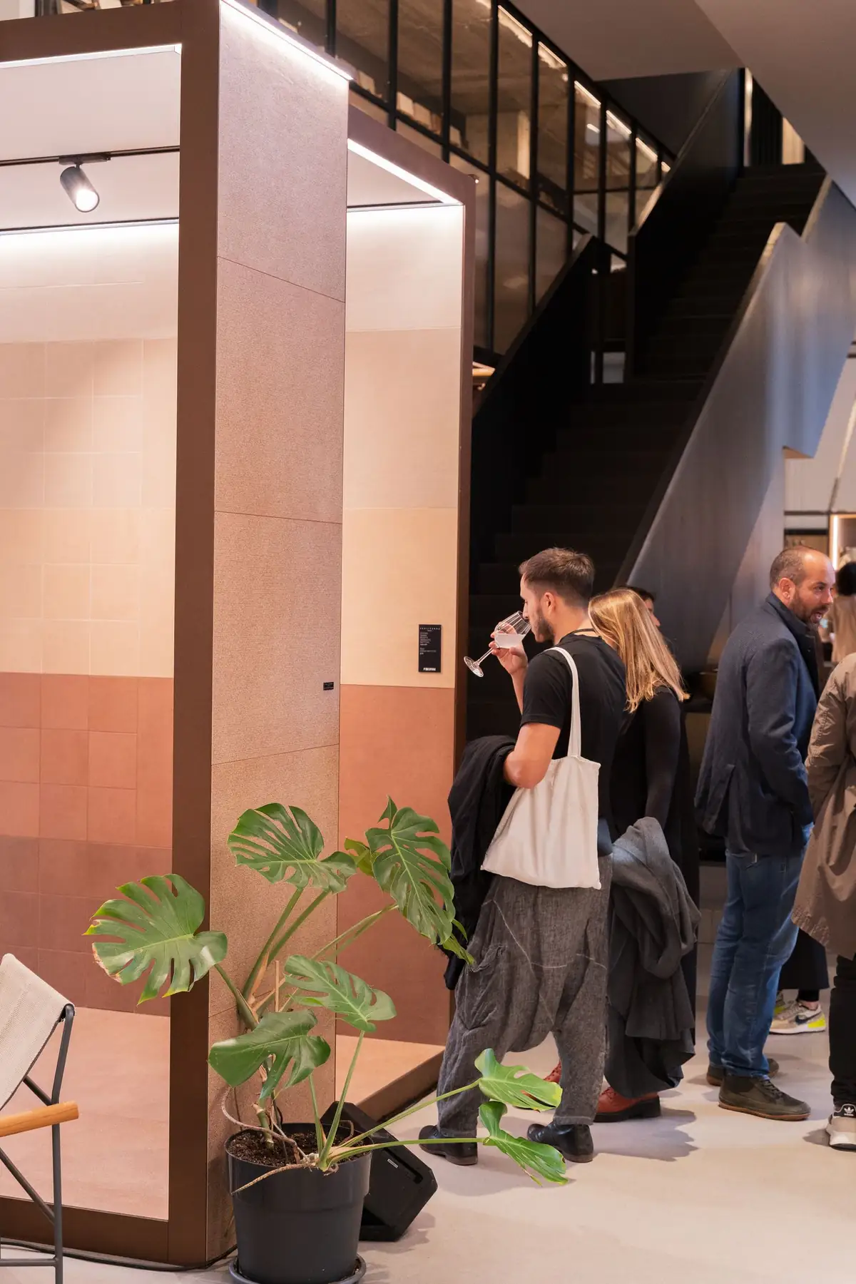 Visitors next to a volume clad in pink and terracotta tones