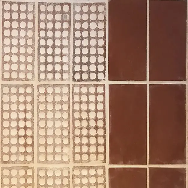 Detalle de una pared con piezas cerámicas perforadas de agujeros vistos junto a piezas lisas de color rojo