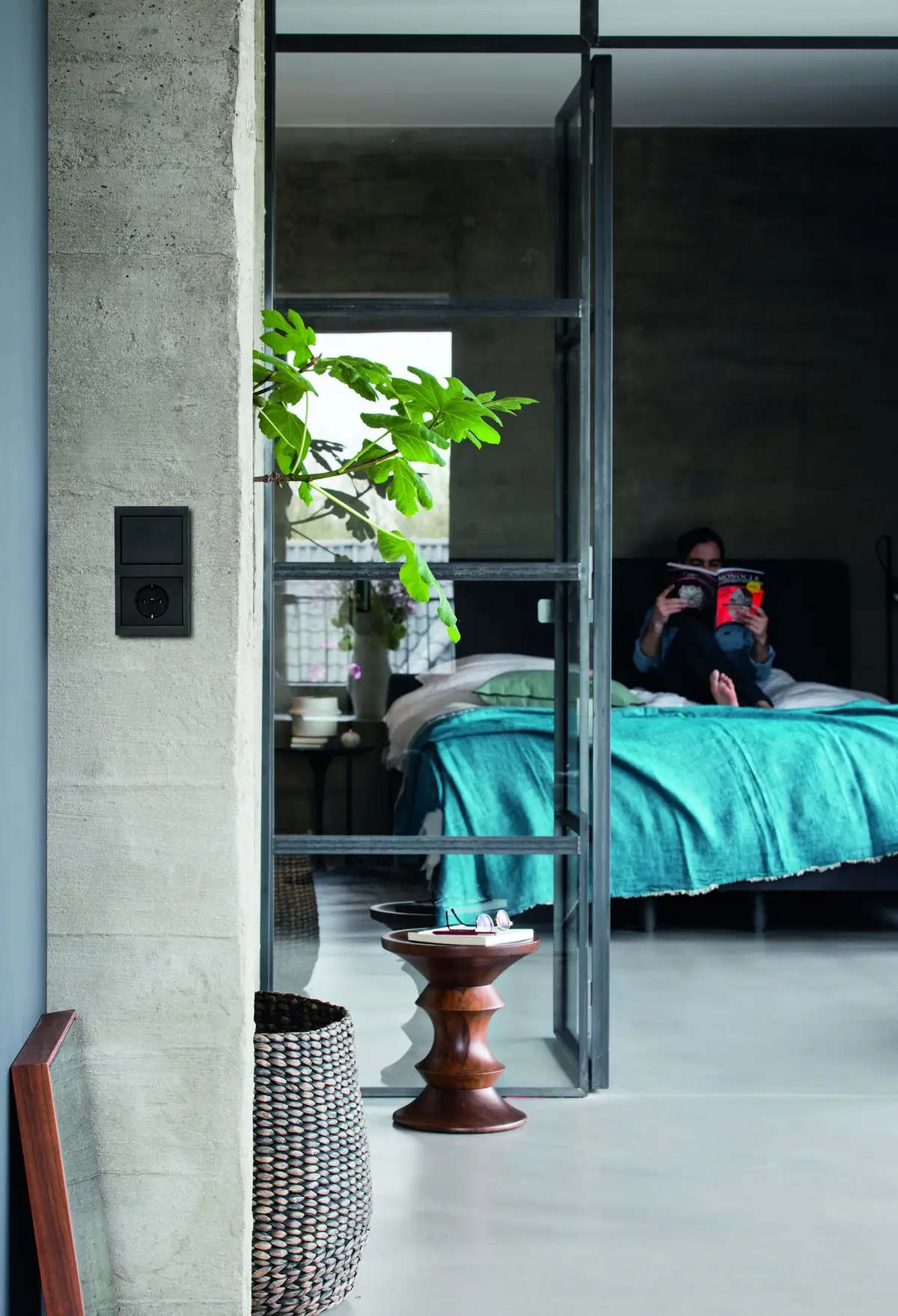 Black switch and socket on a concrete column, beside a bedroom separated by a glazed partition