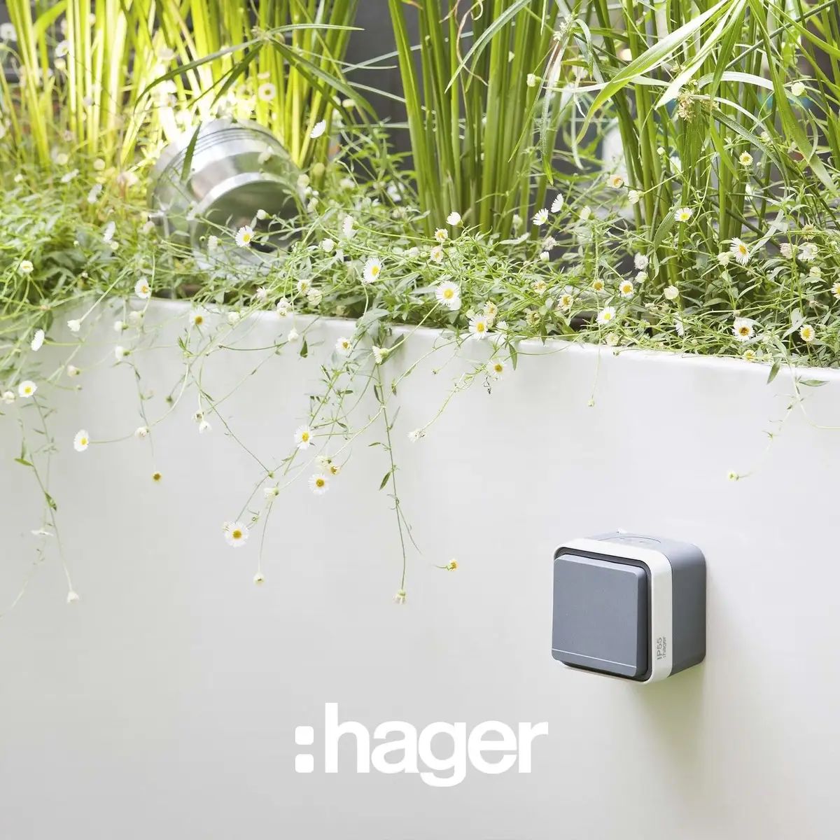Grey cubyko IP55 weatherproof switch on the white wall of a flower planter
