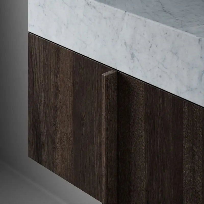 Detail of a veined white marble washbasin on a dark oak unit with a vertical handle in the same wood.