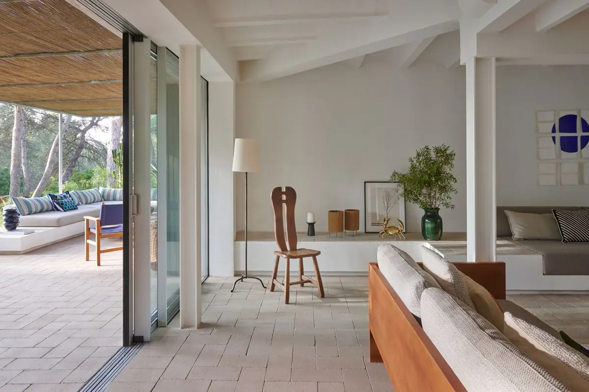 Living room opening onto a porch with a continuous white compacted stone floor